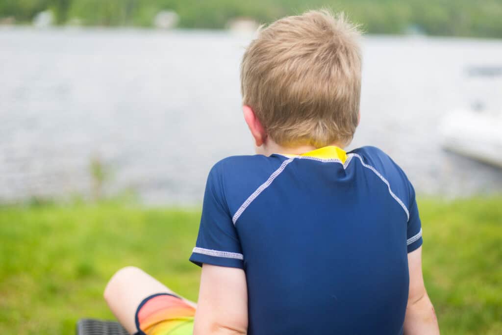 young boy back turned looking out over lake