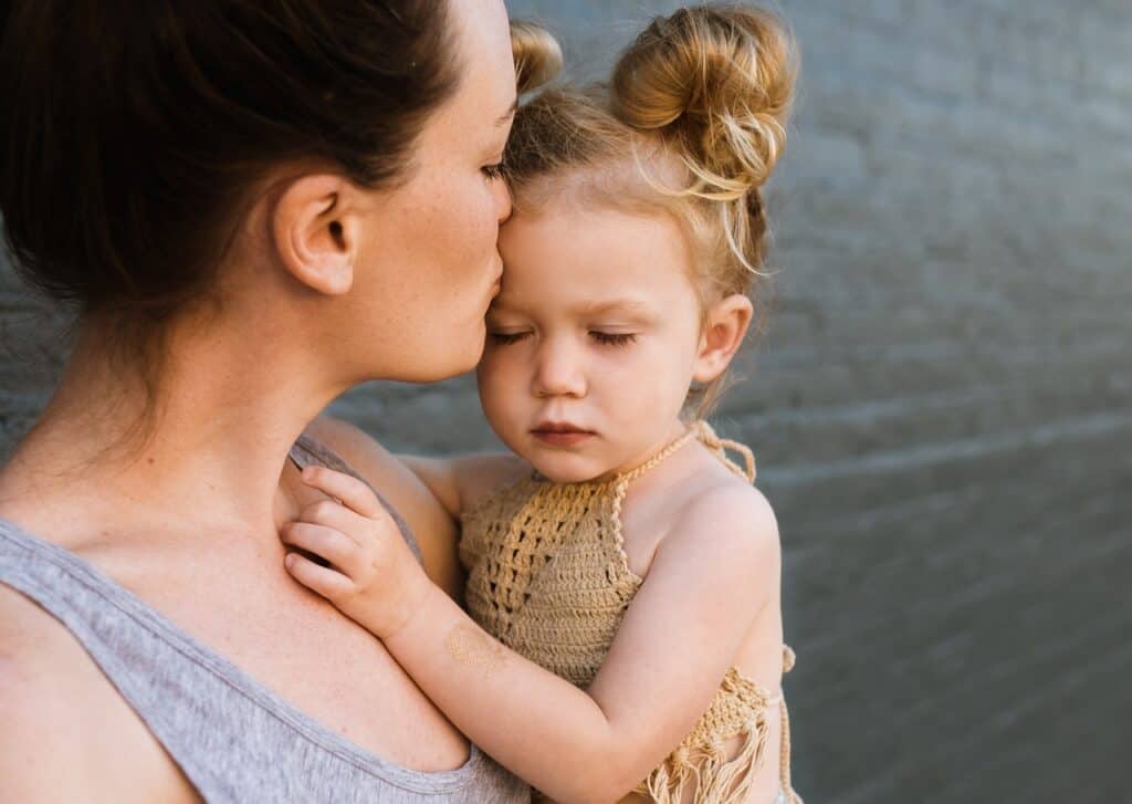 Woman holding little girl who looks unhappy