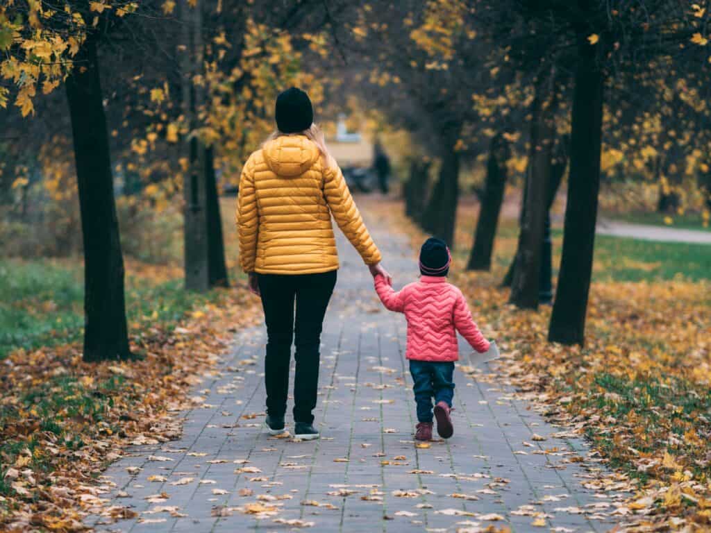 Woman and child walking on path on fall day