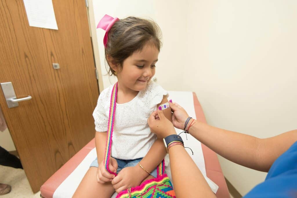 Little girl getting bandaid on arm after vaccination
