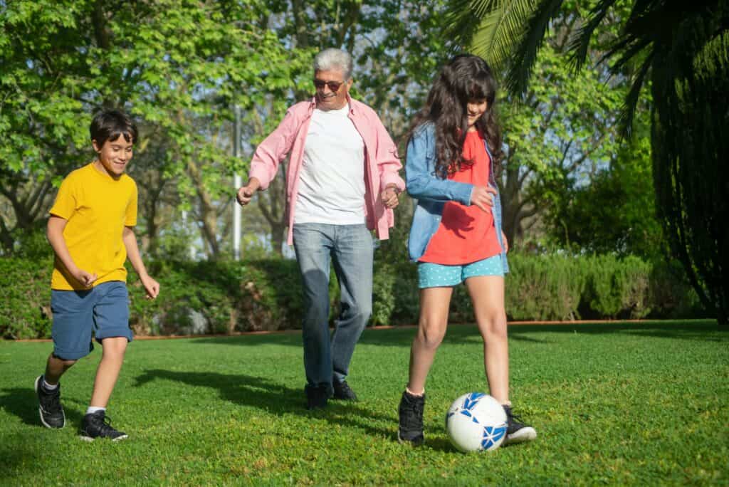 man playing soccer with grandkids
