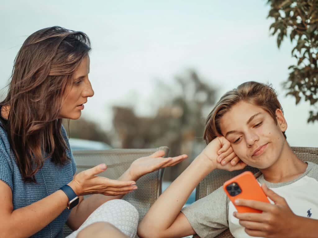 mom talking to teen who is smirking and looking at phone