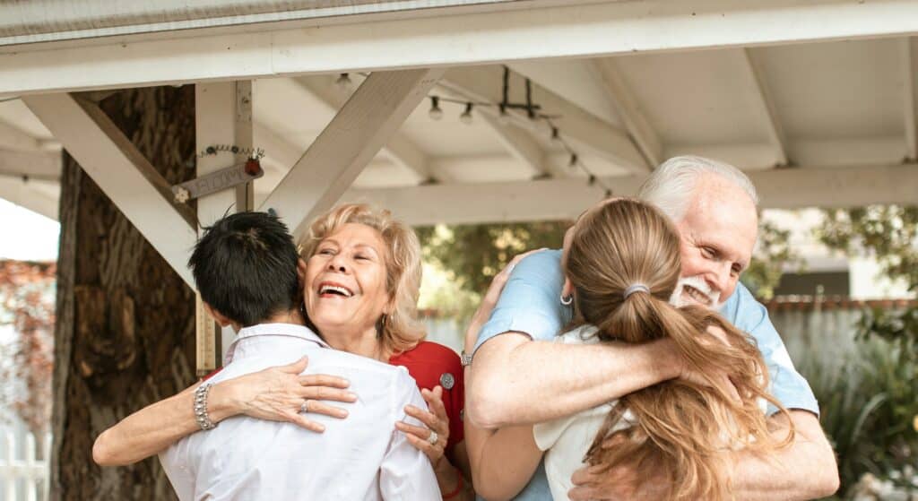 man and woman hugging older couple