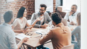 Team of men and women sitting around a table exemplifying the biblical view of work, which is others centered