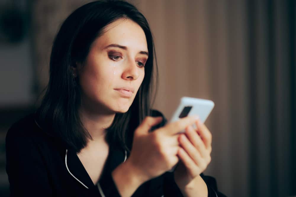 A sad woman looking at her phone